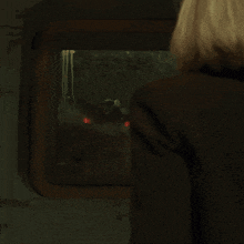 a woman looks out a window at a spider