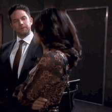 a man in a suit and tie is hugging a woman in a paisley shirt