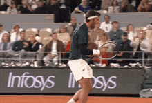 a tennis player holds a tennis racquet in front of an infosys sign