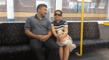 a man and a woman are sitting on a bus with the word yale on the wall behind them