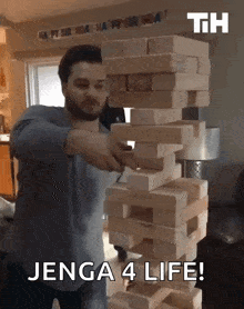 a man stacking wooden blocks with the words jenga 4 life
