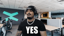 a man wearing headphones and a black shirt with the word yes on it