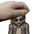 a hand is holding a statue of a man with a beard on his head .