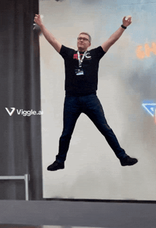 a man in a black shirt is jumping in the air with his arms outstretched in front of a sign that says viggle.ai