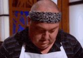 a man wearing an apron and a headband looks down