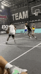 a group of people are playing basketball on a court with a sign that says team on it .