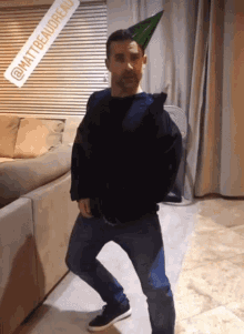 a man wearing a party hat is standing in a living room
