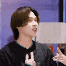 a man in a black shirt is making a peace sign with his hands