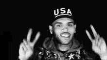 chris brown is wearing a usa hat and making a peace sign .