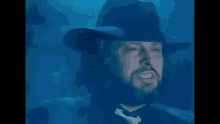 a man in a black hat is surrounded by smoke in the dark