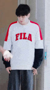 a man wearing a fila shirt is standing next to a door