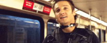 a man is riding a train with a gun around his neck and talking .