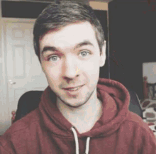 a man in a red hoodie is taking a selfie in a room .
