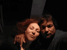 a man and a woman are posing for a picture in a dark room