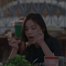 a woman is sitting at a table with a spoon in her mouth eating food .