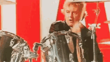 a man is playing drums in front of a red white and blue background .