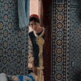 a young man is peeking out of a doorway .