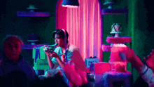 a man is sitting at a table eating a piece of cake in a neon room