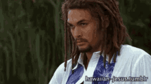 a man with dreadlocks and a beard is wearing a white shirt and blue tie .