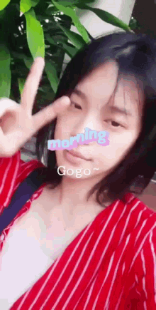 a woman in a red and white striped shirt is giving a peace sign