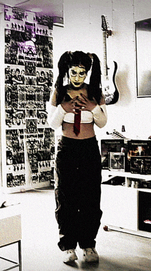 a woman wearing a mask and a tie is standing in front of a guitar