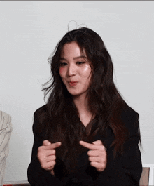 a woman with long hair is making a funny face with her hands