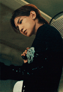 a woman in a black sweater is holding a tennis racket