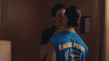 a man in a purple shirt and a woman in a blue shirt are hugging each other