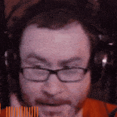 a man wearing glasses and headphones has a beard