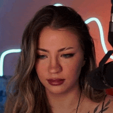 a woman with a nose ring is sitting in front of a microphone and making a funny face .