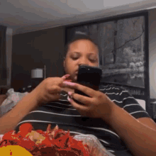 a woman is eating crawfish while looking at her cell phone