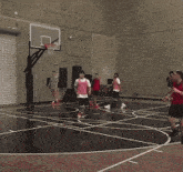 a group of people are playing basketball in a gym and one of them is wearing glasses