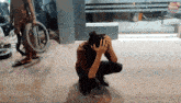 a person kneeling down with their head in their hands in front of a glass door that says " read monthly "