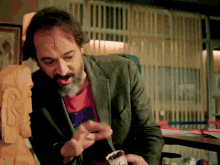 a man with a beard wearing a green jacket and a red t-shirt that says ' a ' on it