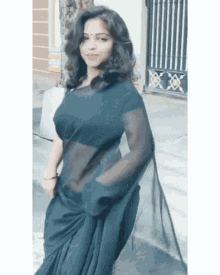 a woman wearing a black saree is standing in front of a building