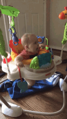 a baby sitting in a fisher price jumperoo