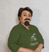 a woman with a fake beard and mustache is wearing a green shirt with a dinosaur on the front