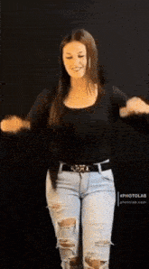 a woman wearing ripped jeans and a black top dancing