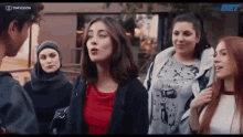 a group of young women are standing next to each other on a sidewalk .