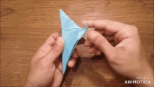 a person is holding a blue origami object and the words made in animatica are visible