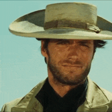a man with a beard wearing a cowboy hat and a black shirt .
