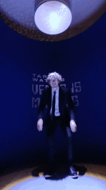 a man in a suit and tie is dancing in front of a sign that says ' taf wars ' on it