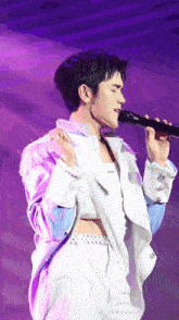 a man singing into a microphone while wearing a white jacket