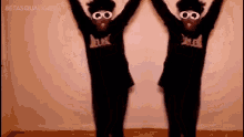 two people are standing next to each other with their arms in the air and wearing glasses .