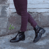 a person wearing purple pants and black boots walking