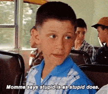 a young boy is sitting on a bus and says `` momma says stupid is as stupid does . ''