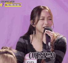 a woman singing into a microphone with a sign that says honeycam.org on it