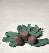 a leaf made of green clay with three brown balls on it