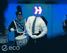 a man in a marching band is playing drums with a blue h on his head