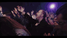 a blonde woman singing into a microphone with a crowd behind her